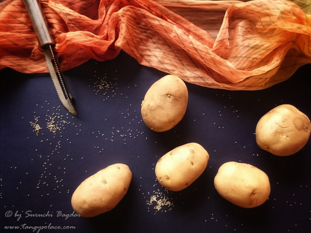 whole potatoes on navy blue backdrop orange fabric and peeling knife