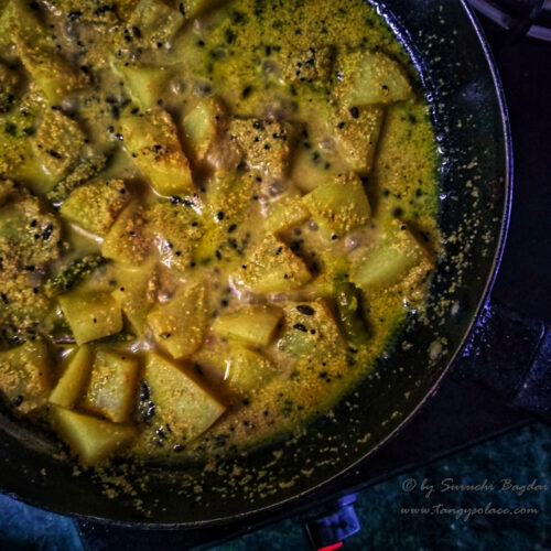 close up of aloo poshto simmering in nonstick pan