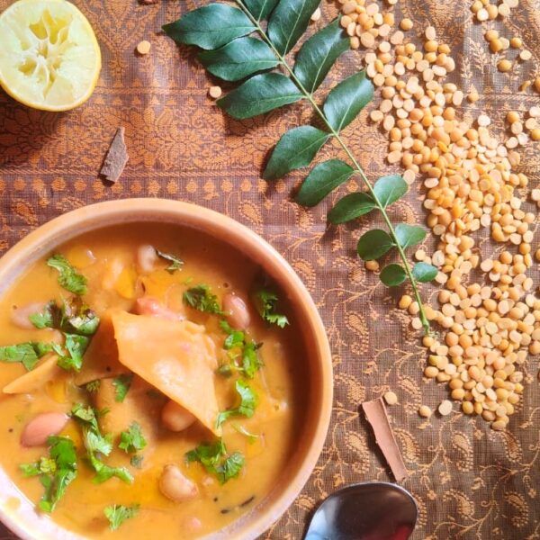 bowl of dal dhokli styled with squeezed lemon , curry leaf stalk , spoon and pigeon pea lentils