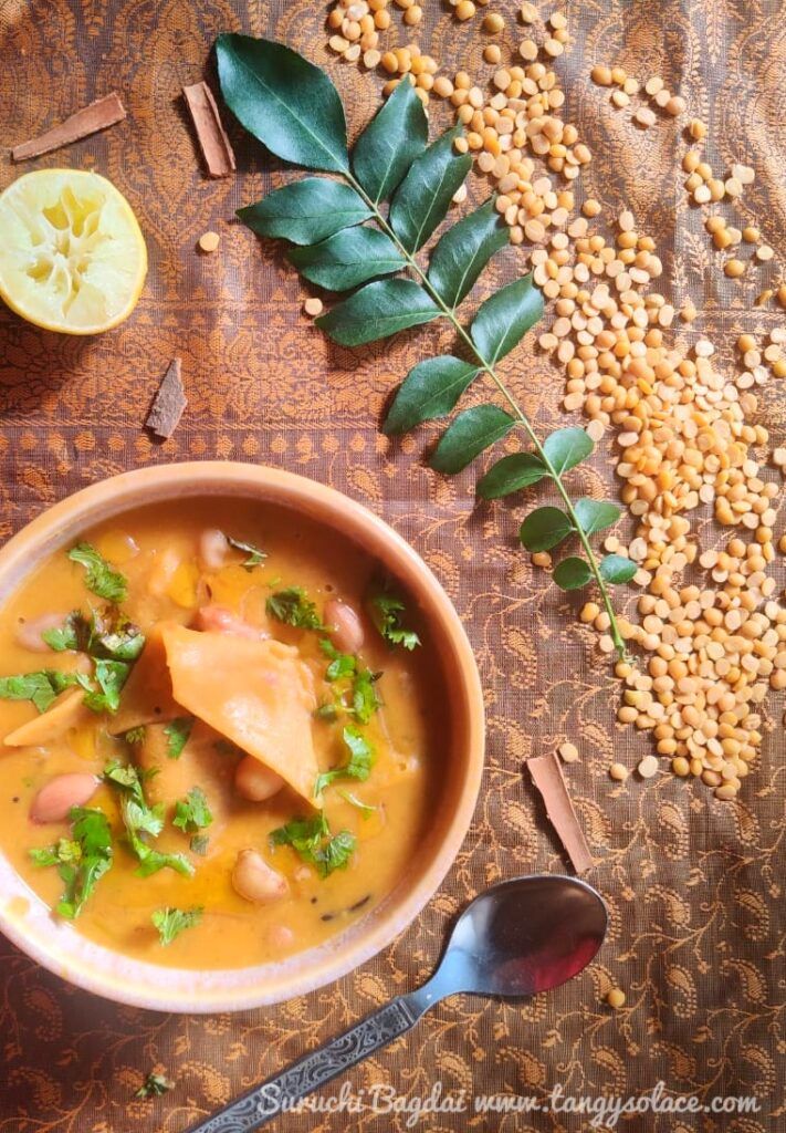 bowl of dal dhokli styled with squeezed lemon , curry leaf stalk , spoon and pigeon pea lentils