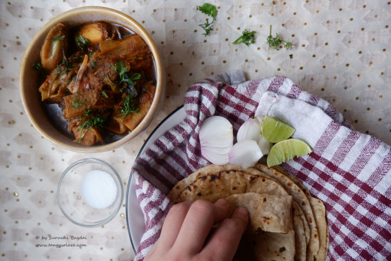 Jackfruit curry in bowl with phulka, onion , lemon on white background and red duster