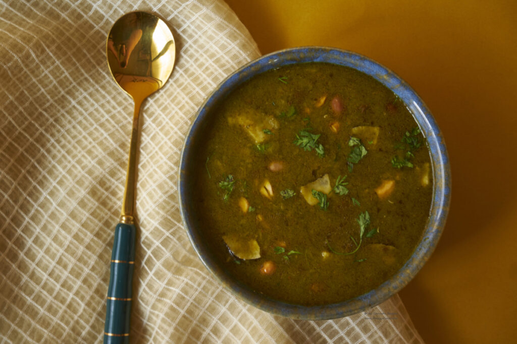 A bowl of mirchiya bhaji with a golden spoon