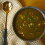 A bowl of mirchiya bhaji with a golden spoon