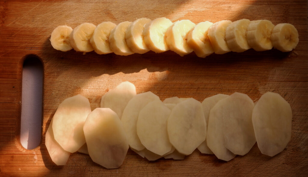 banana and thin potato slices on chopping board