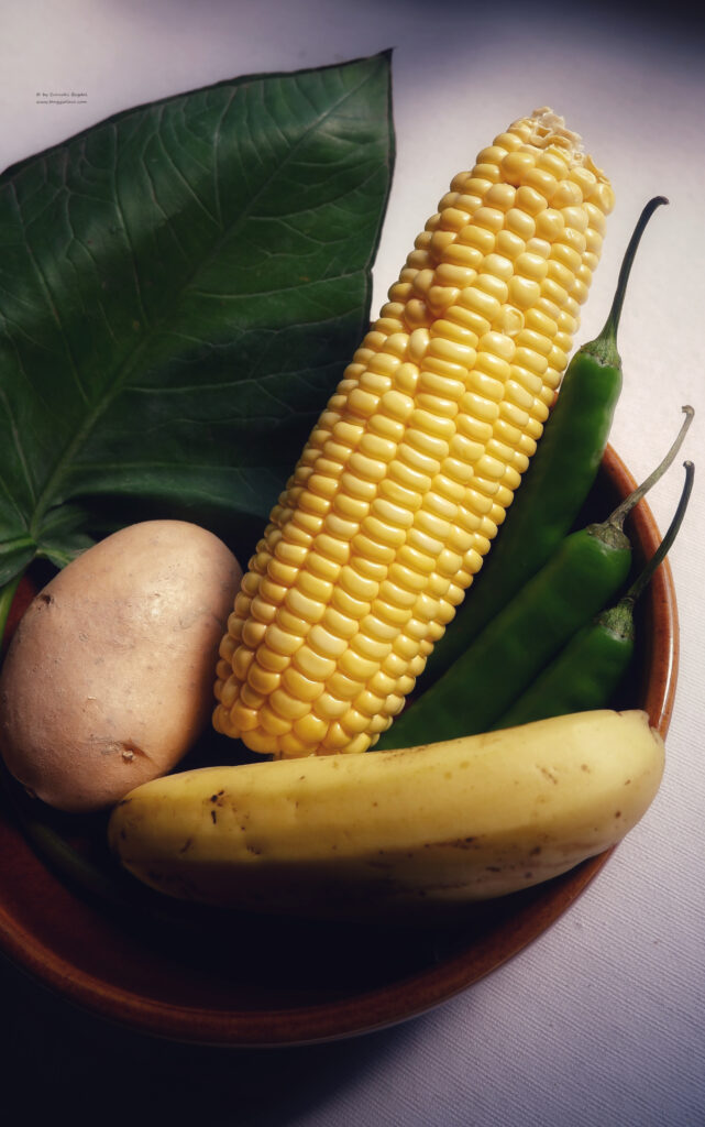 corn, chillies, potato, banana and colocasia on a brown bowl