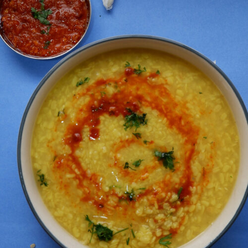 urad dal with chutney swirl on top on blue backdrop