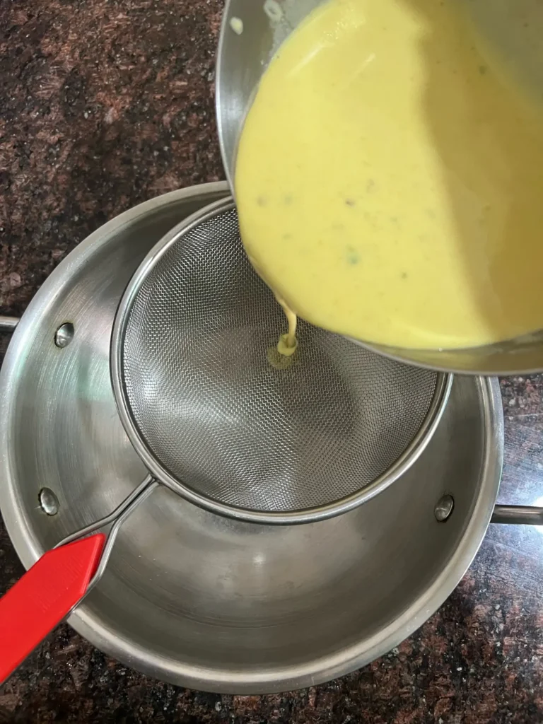 straining the khandvi batter via sieve directly into kadhai